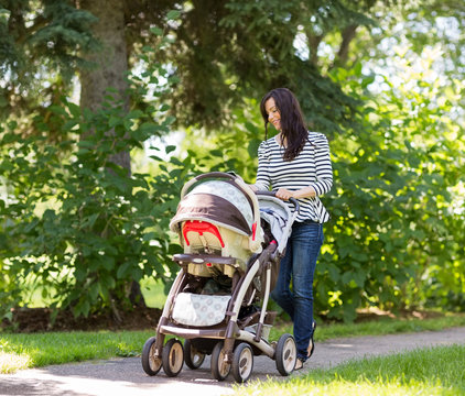 Woman Pushing Baby Carriage In Park