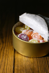 Sweet candies in metal can, on wooden background