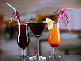 Glasses of tasty cocktails on bright background