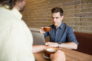 Man and Friend in Coffee Shop Using Computer