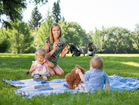 Mother Photographing Children In Park