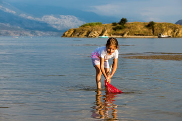 Beautiful little girl on the beach fishes