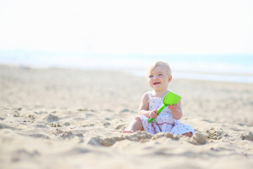 Cute baby girl plays on sandy beach