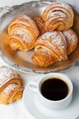 Coffee with fresh croissants on wooden table still life