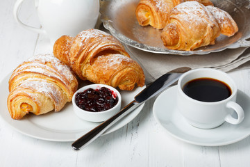 Croissants with jam and coffee on wooden table still life