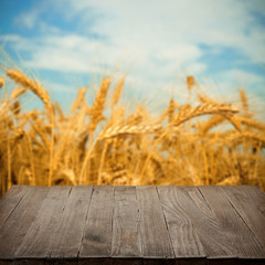 Empty wooden table with wheat field