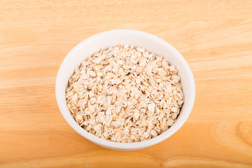 Dry Oats in White Bowl on Wood Table