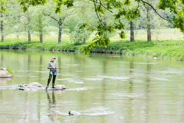 Fototapeta na wymiar woman fishing in Sazava river, Czech Republic