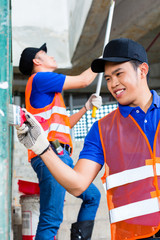 Obraz premium Asian Painter with brush and paint on construction site