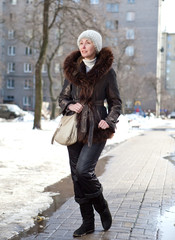 young woman in  jacket with fur collar on street in the winter