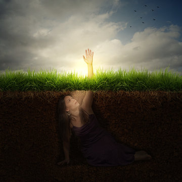 A woman buried under ground reaching out for help.