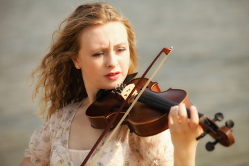 Portrait blonde girl with a violin outdoor