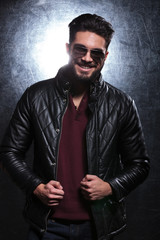 man pulling on his leather jacket and smiles