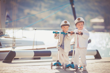 Two little boys riding on scooter bicycle in summer