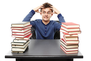Angry stressed student sitting at his desk with hands on the hea