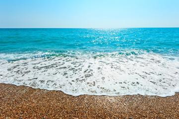 foamy wave rolls on a sandy beach