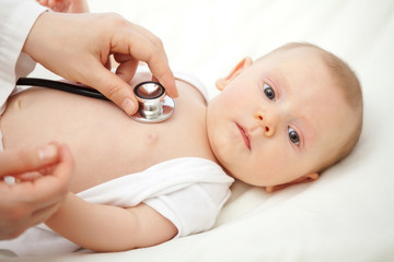  pediatrician visits a very young Caucasian child with a stethoscope. concept of childcare and...