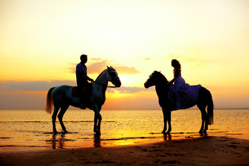 Two riders on horseback at sunset on the beach. Lovers ride hors