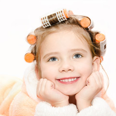 Portrait of smiling cute little girl in hair curlers and bathrob