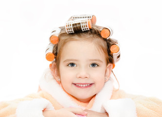 Portrait of smiling cute little girl in hair curlers and bathrob