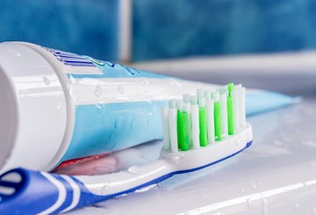 A toothbrush next to a tube of toothpaste at the sink