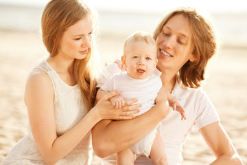 Family at a picnic on the beach. Mother, father and baby near th
