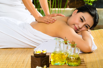 Obraz na płótnie Canvas Asian woman having a massage in tropical setting
