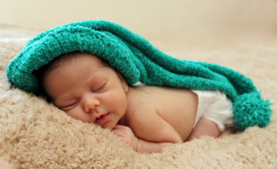 newborn baby is wearing a blue hat and laying down sleeping
