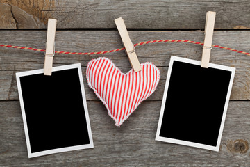 Two blank instant photos and red heart hanging on the clotheslin