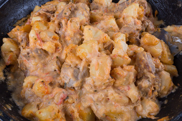 stewed potatoes with meat in a cast iron bowl