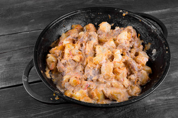 stewed potatoes with meat in a cast iron bowl