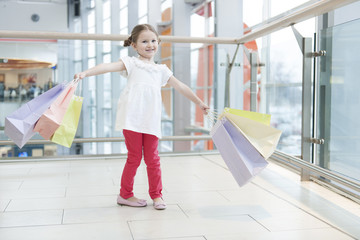 Young girl laden with paper shopping bags
