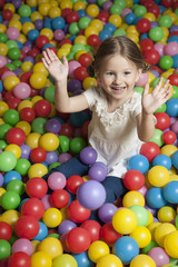 Fototapeta na wymiar Young girl in ball pit throwing colored balls