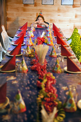 Obraz premium Bored young girl at head of fully set but empty birthday table