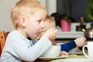 Boys kids children eating corn flakes breakfast at the table
