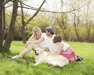 Obraz premium Family sitting in park with dog