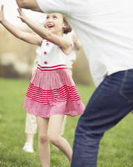 Father mother and daughter throwing ball to each other in the park