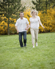 Couple running through park holding hands