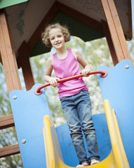 Young girl standing at top of slide in playground
