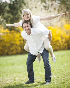 Man Piggybacking Woman In Park