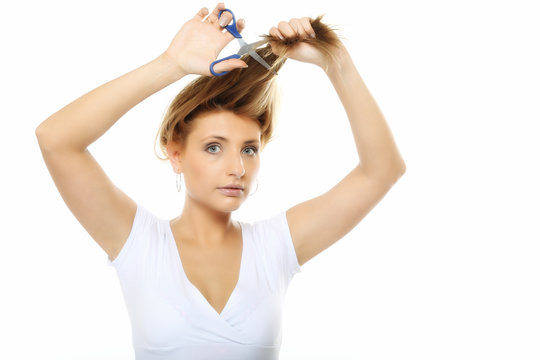 Unhappy woman cutting her hair with scissors isolated