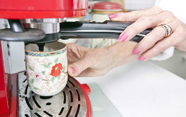 Cropped image of woman dispensing coffee from machine in kitchen
