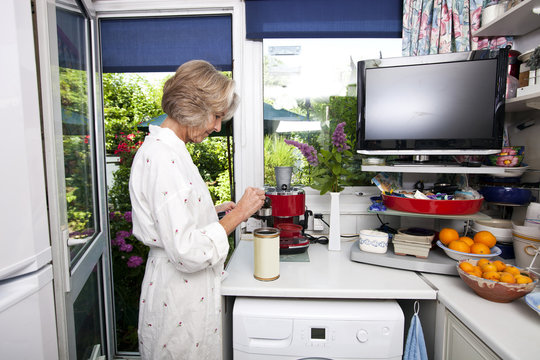 Side view of senior woman filling ground espresso in holder at kitchen