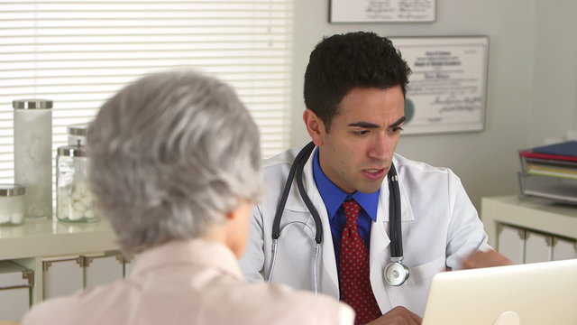 Hispanic doctor talking to elderly patient