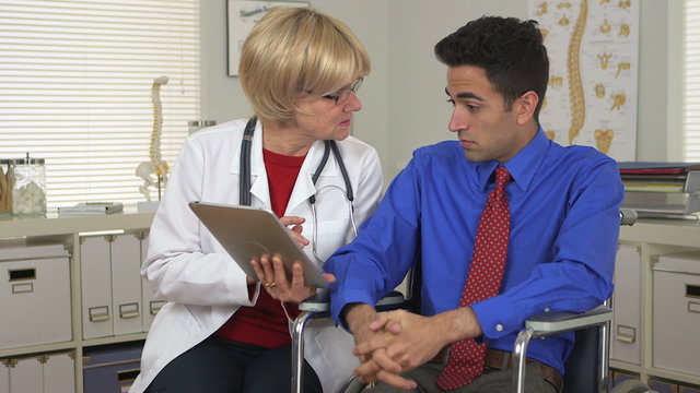 Doctor talking to disabled Mexican patient with tablet