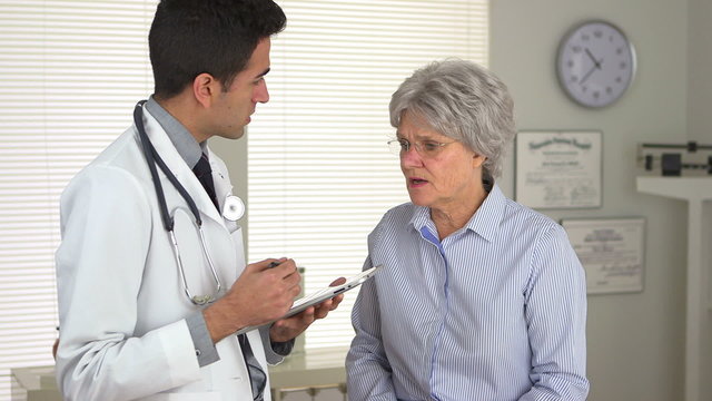 Mexican doctor talking to mature woman with tablet