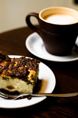 A cup of coffee in brown cup and cheese cake for breakfast