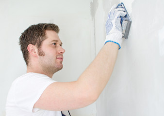 Male plasterer in uniform polishing the wall.
