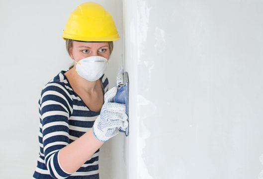 Female plasterer polishing the wall. Place for your text.