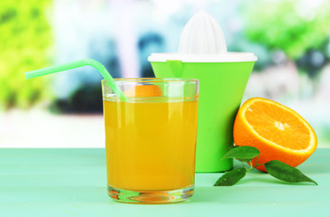 Citrus press, glass of juice and ripe orange